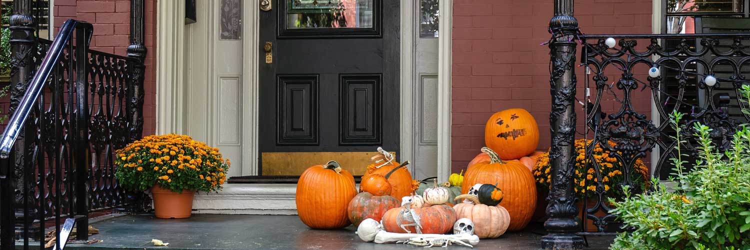 Front porch in the fall, with orange flowers, pumpkins, and Halloween deocrations.