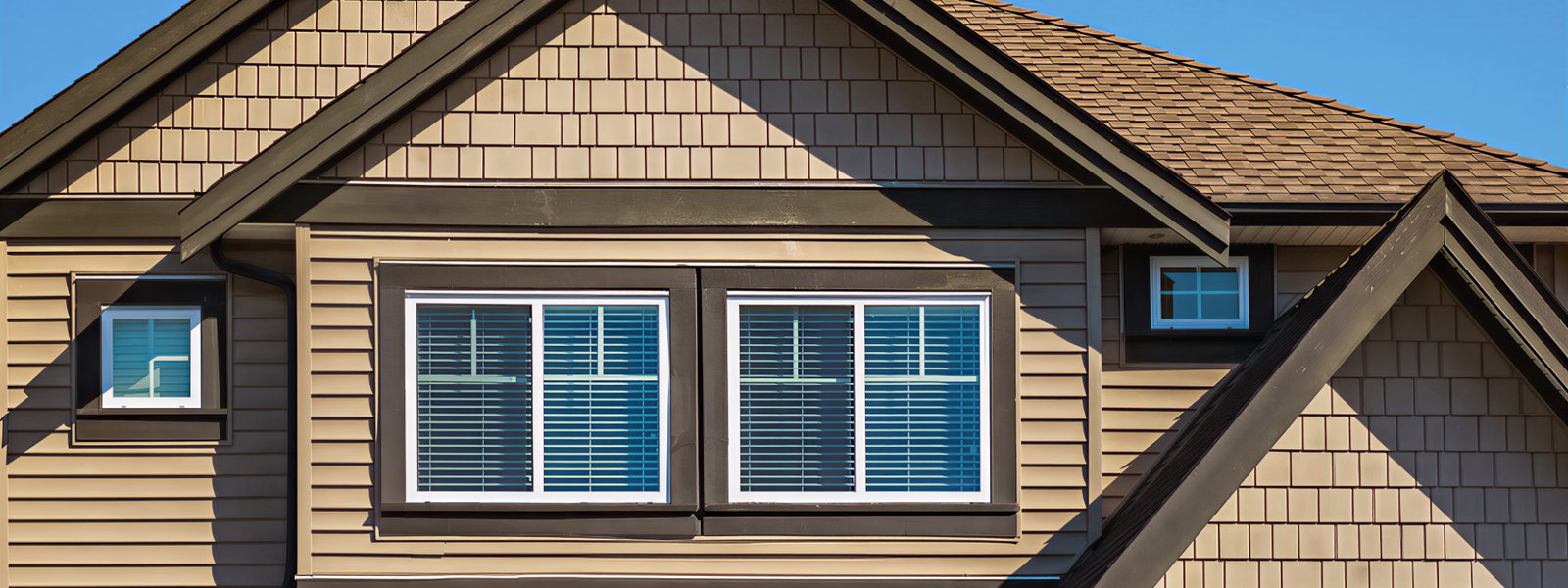 Craftsman-style home exterior with white windows set in dark trim under shingled gables